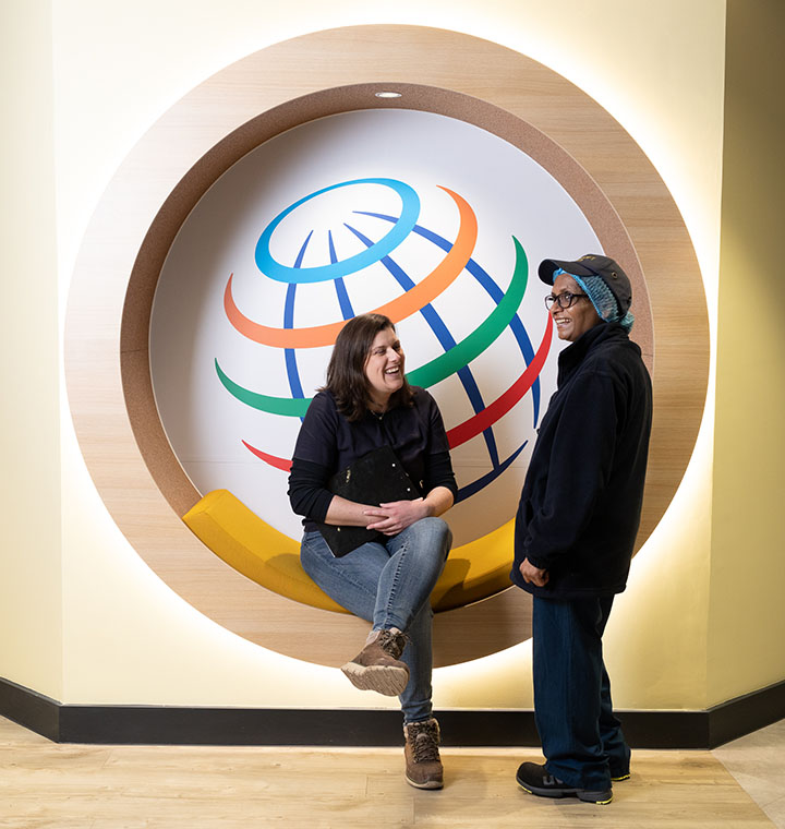 Two employees in front of the PepsiCo globe logo